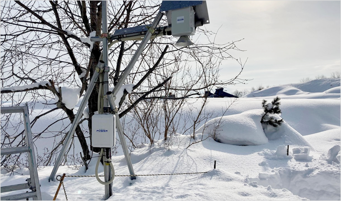 積雪深度監視を行うために木にかけられている当社オリジナル屋外用電源BOX「ALPHIoT POWER」